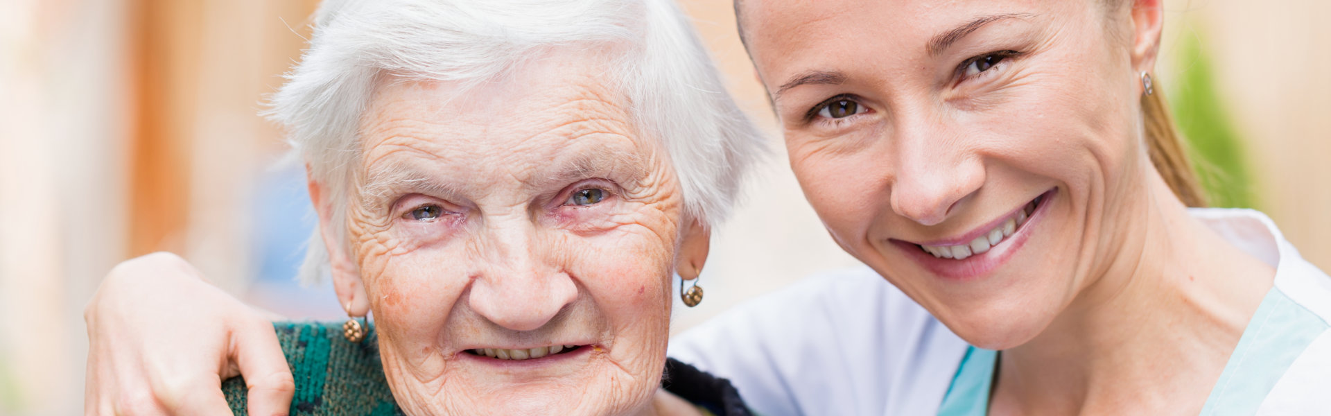 Elderly woman and female caregiver smiling