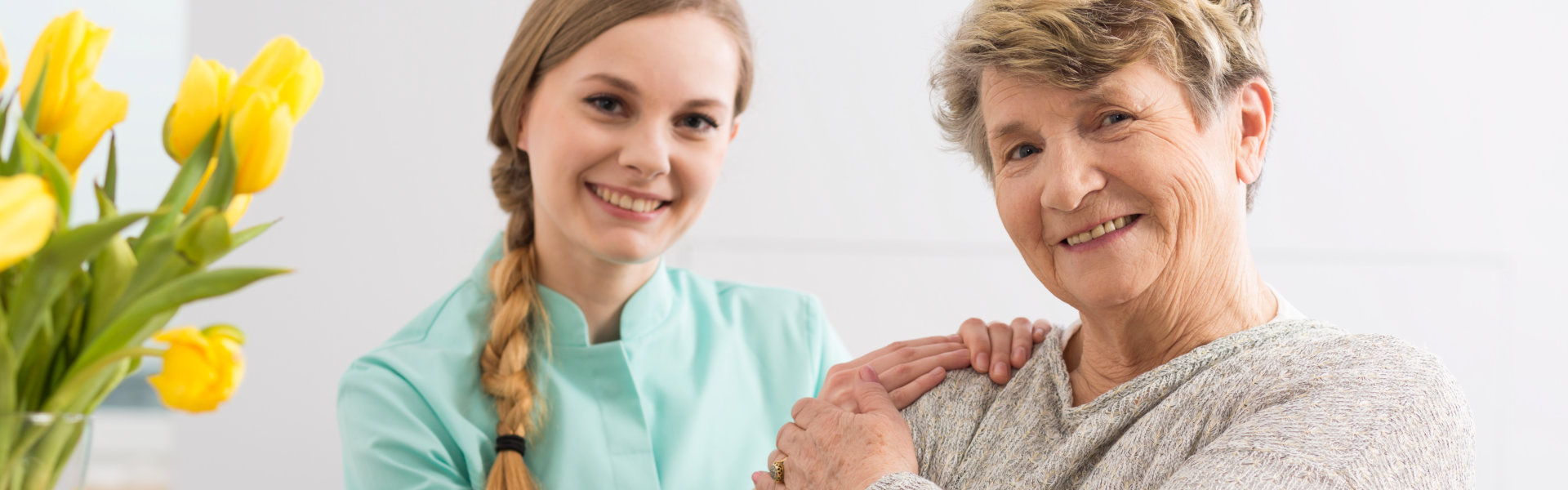 Female caregiver and elderly woman smiling